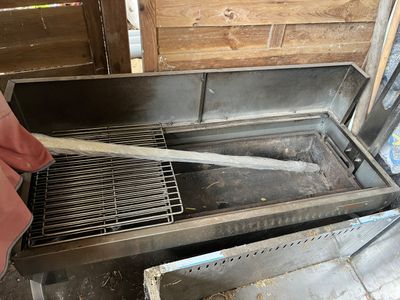 a large metal grill with a wooden handle on it