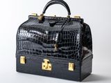 an image of a black crocodile skin bag with gold hardware
