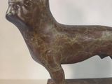 bronze statue of a dog on a stand on a white surface