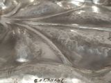 a silver plate that has a leaf design on it