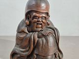 une vieille statue en bois représentant un homme assis sur une table