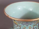 a blue vase with a gold rim sitting on a table
