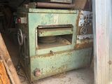 a green oven sitting inside of a building next to a pile of wood