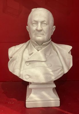 white marble bust of a man in a suit on a red surface