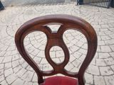 a wooden chair with a red seat sitting on a sidewalk
