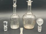 three glass bottles and a glass stopper on a table