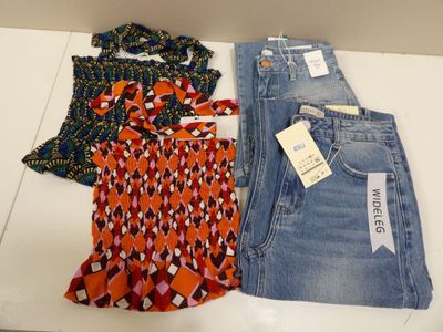 trois paires de jeans pour femme et un chemisier sont posés sur une table