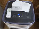 a small air conditioner sitting on the floor next to a remote control