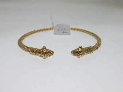 gros plan d'un bracelet en or sur une surface blanche