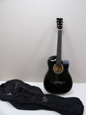 une guitare noire et un sac noir posés sur une table blanche