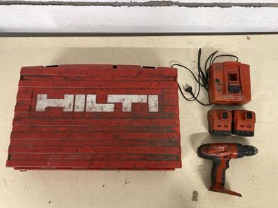 a drill and two batteries sitting on a table