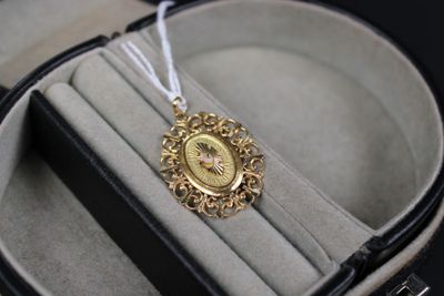 a small gold clock in a case with a white string