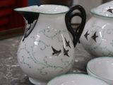 a white and green pitcher and bowls on a table