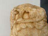 a stone statue of a head on display in front of a white wall