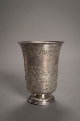 une coupe en argent ancien posée sur un socle, sur fond gris