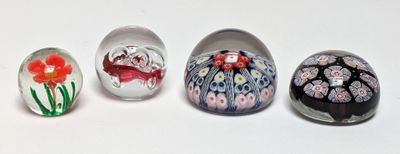 four glass eggs with different designs are lined up on a white surface