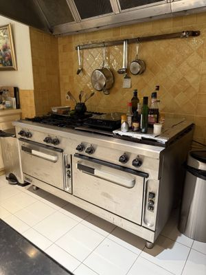 a kitchen with a stove, oven, and a trash can