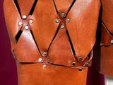 a close up of a brown leather jacket hanging on a wall