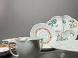 many plates and cups sitting on a table with a vase