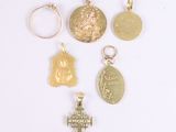several gold and silver charms including a cross, a medal, a medal, and a medal