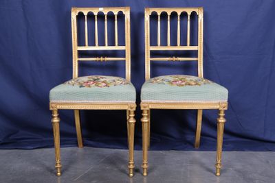 une paire de chaises anciennes dont les assises sont recouvertes d'un tissu à motifs floraux, sur fond bleu