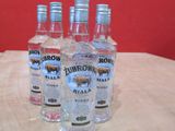 quatre bouteilles de vodka posées sur une table, avec un mur rouge en arrière-plan