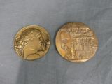 two gold medallions depicting a woman and a castle