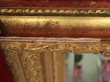 a mirror with a gold frame and a tie hanging on it
