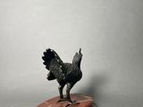 statue of a rooster on a wooden base on a gray background