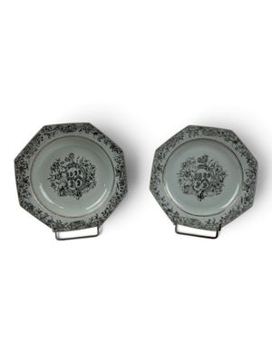 two plates with black and white designs on them on a white surface