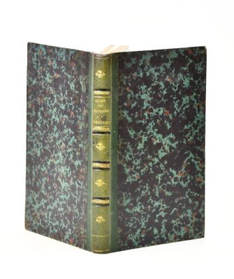 an old book with a green cover sitting on top of a white table