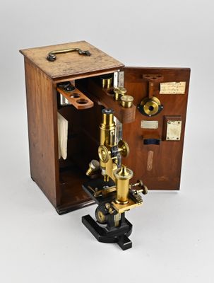 un vieux microscope avec un étui en bois et une poignée en métal