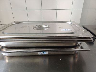des bacs alimentaires en acier inoxydable empilés les uns sur les autres sur un plan de travail de cuisine