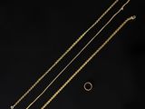 trois chaînes en or et une bague sur fond noir