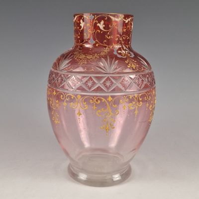 un vase en verre rose orné d'un motif doré