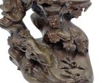 bronze statue of a man on a rock with a bird in his hand