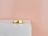un gros plan d'une bague en or posée sur un bloc blanc