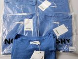 quatre t-shirts bleus dans des sacs en plastique posés sur une table