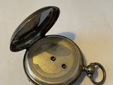a silver pocket watch sitting on a white surface