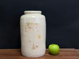 a white vase sitting on a wooden table with an apple next to it