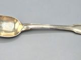 a silver spoon with a spoon handle on a gray surface
