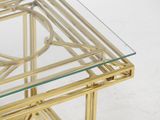 gold metal and glass coffee table with a glass top on a white background