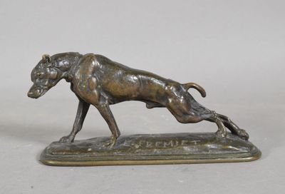 a bronze statue of a dog running on top of a wooden base
