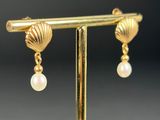 a close up of a pair of gold earrings with pearls on them