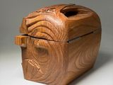 carved wooden box with lid and handle on a white surface