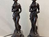 pair of bronze statues of a woman and a man on a pedestal