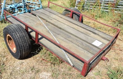 a trailer with a wooden cart attached to it in the grass