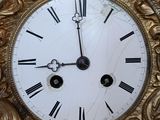 a gold clock with roman numerals on the face