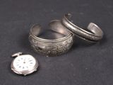 deux bagues en argent et une montre en argent posées sur une surface noire