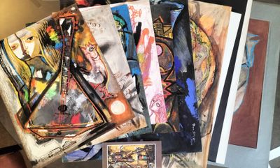 a pile of paintings on a table next to a clock